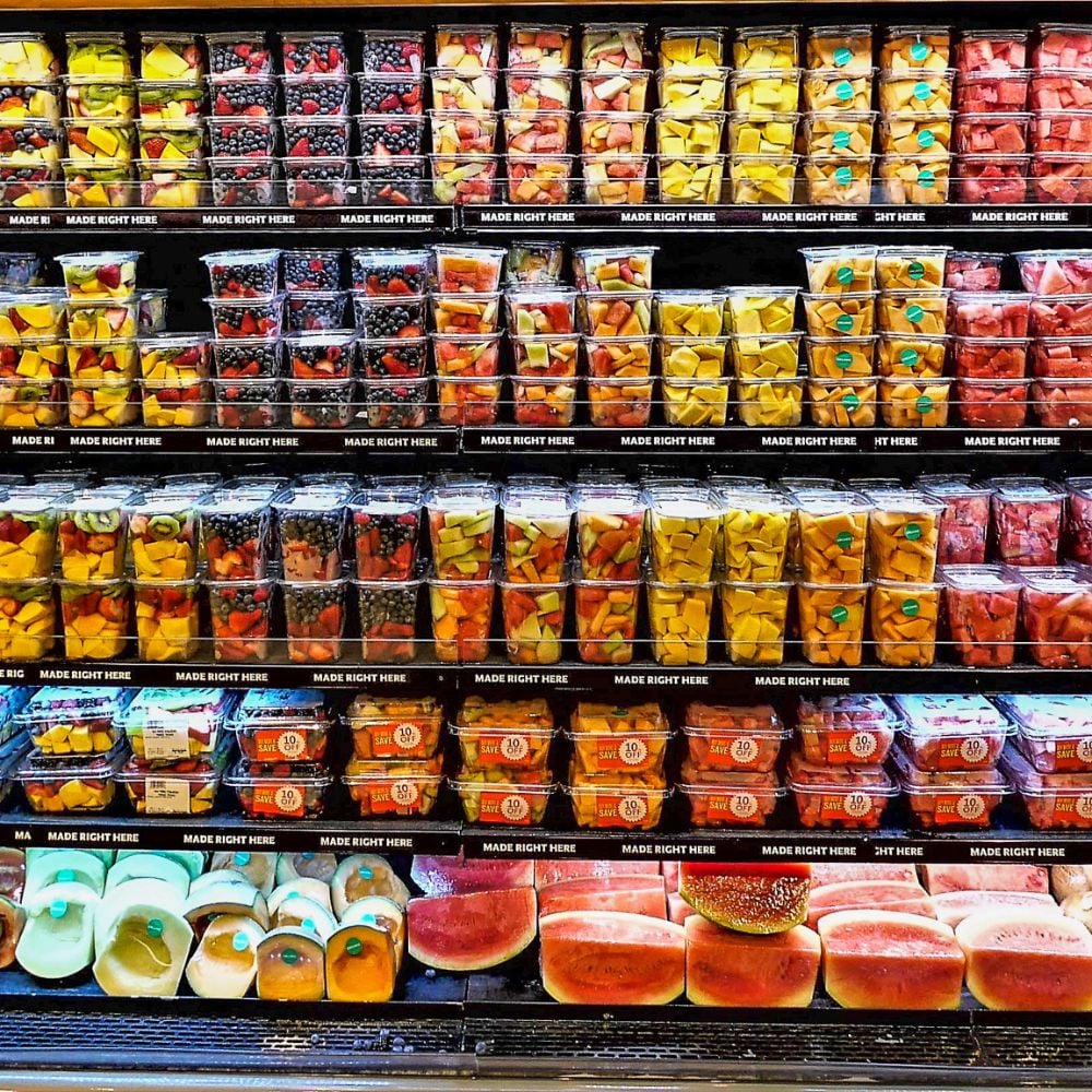 Packaged fresh fruit containers displayed on shelves inside a grocery retail store